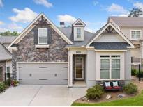 Charming home featuring a stone facade, two-car garage, and a cozy front porch with a bench at 307 Serenity Way, Woodstock, GA 30188