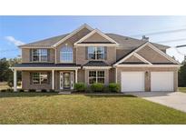 Charming two-story brick home featuring a well-manicured lawn, two-car garage and beautiful landscaping at 191 Kyndal Dr, Hampton, GA 30228