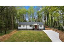 Charming single-story home featuring a red door, black shutters and a spacious, well-manicured front yard at 2798 Hutchins Rd, Lawrenceville, GA 30044