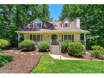Charming home featuring a cozy front porch and beautifully landscaped yard with lush greenery at 4150 Kalb Sw Ct, Smyrna, GA 30082