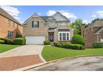 Charming brick two-story home featuring a well-manicured lawn, attached garage and manicured bushes at 2321 Norbury Se Cv, Smyrna, GA 30080