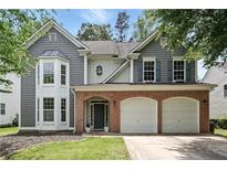 Charming two-story home featuring a brick facade, gray siding, and a two-car garage at 4975 Skyland Pkwy, Cumming, GA 30028