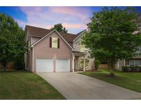Charming two-story home featuring a two-car garage, well-maintained lawn, and lush trees at 4515 Ambassador Way, Cumming, GA 30040