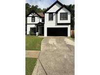 Charming two-story home featuring a black garage door and a well-manicured lawn at 2111 Nelms Pointe Lndg, Lawrenceville, GA 30043