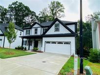 Charming two-story home boasts a two-car garage, black trim, and lush landscaping at 1540 Ox Bridge Ct, Lawrenceville, GA 30043