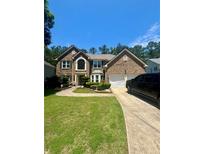 Charming brick two-story home with manicured landscaping, driveway, and a two-car garage at 7625 Cedar Grove Ct, Fairburn, GA 30213