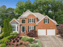 Beautiful two-story brick home with lush landscaping, a two-car garage, and dark green shutters at 2026 Cresthaven Walk, Woodstock, GA 30189