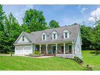 Charming two-story home features a welcoming front porch, well-manicured lawn, and an attached two-car garage at 410 Hendon Rd, Woodstock, GA 30188