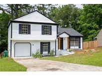 Charming two-story home featuring a well-maintained lawn, garage, and black and white accents at 5072 Plantation View Trl, Stone Mountain, GA 30088