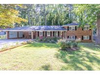 Charming brick home with a well-manicured lawn and colorful flowerbeds in a peaceful, wooded setting at 2648 Oswood Dr, Tucker, GA 30084