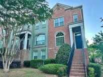 Two-story brick townhome featuring a charming entrance with landscaped front yard at 4875 Carre Way, Alpharetta, GA 30022