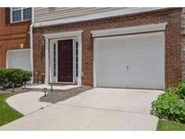 Exterior of townhome with brick facade, driveway, front door, and attached one car garage at 541 Lantern Wood Dr, Scottdale, GA 30079