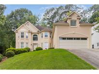 Elegant two-story home showcasing lush front lawn, attached two car garage, and well-maintained landscaping at 2280 Wildwood Lake Dr, Suwanee, GA 30024
