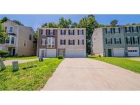 Traditional-style townhome with two-car garage, well-maintained lawn and colorful accents on a sunny day at 6509 Charter Way, Lithonia, GA 30058