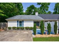 Charming single-story home with white brick, blue shutters and a welcoming, landscaped front yard at 1915 Cooper Landing Se Dr, Smyrna, GA 30080