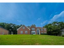 Beautiful brick two-story home with a well-manicured lawn and mature trees at 4495 Riders Ridge Trl, Snellville, GA 30039