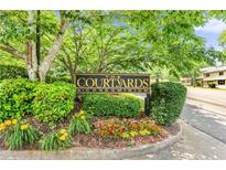 Entrance sign for The Courtyards A Condominium, surrounded by colorful landscaping at 472 Sherman Way, Decatur, GA 30033