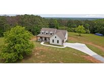 Stunning aerial view of a two-story home with a large yard and long driveway surrounded by dense, mature trees at 1423 Hillcrest Rd, Bowdon, GA 30108
