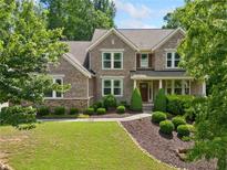 Charming brick home with manicured lawn, complemented by lush trees and impeccable landscaping at 111 Millstone Way, Canton, GA 30115