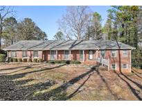 Charming brick home with a well-manicured lawn, complemented by mature trees and a welcoming entrance at 1110 Upper Hembree Rd, Roswell, GA 30076