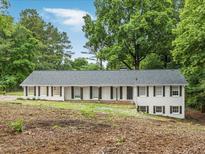 Charming one-story home featuring a light-colored facade, dark shutters, and a neatly maintained landscape at 1110 Upper Hembree Rd, Roswell, GA 30076