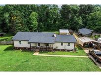 Exterior shot showing a ranch-style home with a covered porch, well-manicured lawn, and detached garage at 140 Wilbanks St, Buford, GA 30518
