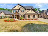 Beautiful two-story brick home featuring manicured lawn and inviting front porch with stone and cedar accents at 704 Rock Springs Rd, Lawrenceville, GA 30043