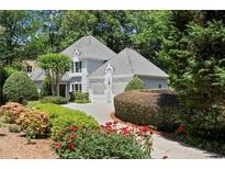 Charming home with a well-manicured front yard, beautiful landscaping, and a gray driveway leading to a two-car garage at 1050 Shady Valley Pl, Atlanta, GA 30324