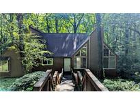 Charming home exterior with a wooden bridge leading to the front door, surrounded by lush greenery and mature trees at 3246 Able Ct, Marietta, GA 30062
