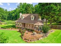 Charming stone home with lush lawn, garden beds, and mature trees, creating a welcoming exterior at 150 Wilbanks St, Buford, GA 30518