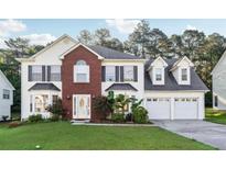 Charming two-story home featuring a red brick facade, well-manicured lawn, and attached two-car garage at 1592 Smithson Ct, Lithonia, GA 30058