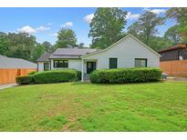 Charming white brick home featuring a lush green lawn, tidy hedges, and solar panels for energy efficiency at 3734 Powers Ferry Nw Rd, Atlanta, GA 30342