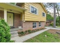 Charming home with a yellow exterior, brick foundation and well-maintained landscaping at 2358 Dabney Ter, East Point, GA 30344