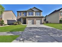 Charming two-story home with brick accents, a well-maintained lawn, and a two-car garage at 581 Collingsworth Ln, Lawrenceville, GA 30043