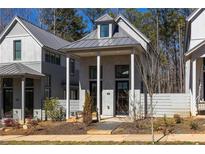 Charming gray cottage style home with inviting front porch and manicured landscaping at 135 Mado Ln, Chattahoochee Hills, GA 30268
