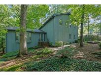 Charming exterior view of the blue two-story home surrounded by mature trees and lush landscaping at 5400 Mill Run Dr, Marietta, GA 30068