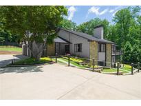 Stylish home exterior with gray brick, stone accents, and a spacious driveway surrounded by manicured landscaping at 9701 Buice Rd, Alpharetta, GA 30022