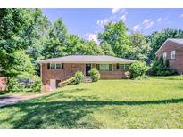 Traditional brick ranch-style home featuring a well-manicured lawn with lush greenery, and inviting curb appeal at 2201 Bollingbrook Drive, Atlanta, GA 30311