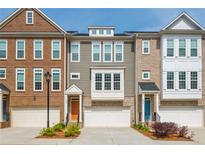 View of townhomes with attached garages, varied brick and siding, manicured landscaping, and colorful front doors at 996 Layton Dr, Buford, GA 30518