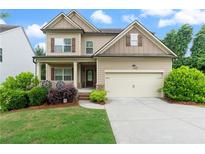 Charming two-story home featuring a two-car garage, inviting front porch, and well-manicured landscaping at 1537 Maplecliff Way, Sugar Hill, GA 30518