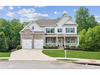 Beautiful two-story home with a brick and white exterior, well-manicured lawn, and an attached two-car garage at 1450 Rainfall Ct, Cumming, GA 30040