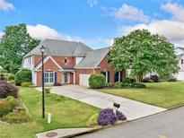 Charming brick home featuring a well-manicured lawn, lush landscaping, and a long driveway at 5365 Glenhaven Dr, Cumming, GA 30041