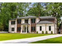 Stunning two-story home with white brick, wood accents, lush lawn, and a concrete driveway at 942 Fairfield, Marietta, GA 30068