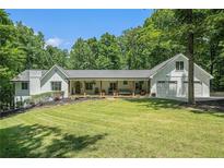 Charming white home with a lush front lawn, a welcoming porch, and an attached three-car garage at 1031 Bailey Rd, Woodstock, GA 30188