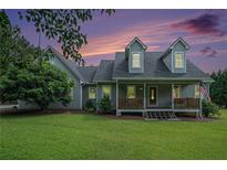 Charming two-story home with a welcoming front porch and lush green lawn at sunset at 225 W Union Grove Cir, Auburn, GA 30011