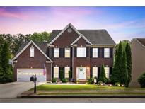 Charming two-story brick home with a manicured lawn and inviting curb appeal during a lovely sunset at 242 Sandhurst Ct, Suwanee, GA 30024