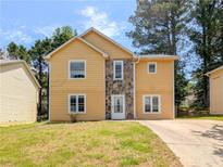 Two-story home featuring a stone facade, yellow siding, a green lawn and a concrete driveway at 2918 Pavia Circle, Austell, GA 30106