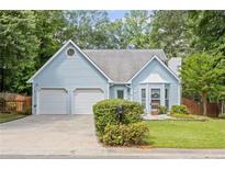 Charming light blue home with a two-car garage and landscaped front yard, blending suburban charm with curb appeal at 4038 Sharon Woods Dr, Powder Springs, GA 30127