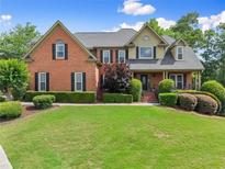 Charming brick home with a well-manicured lawn and lush landscaping adding to the curb appeal at 4955 Winding Rose Dr, Suwanee, GA 30024