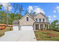 Stunning two-story brick home featuring a three-car garage, manicured lawn, and classic architectural details at 910 Melody Ridge Ln, Buford, GA 30518